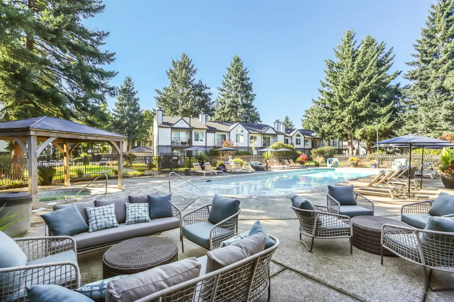 Outdoor pool area with comfortable seating, umbrellas for shade, and poolside lounge chairs.