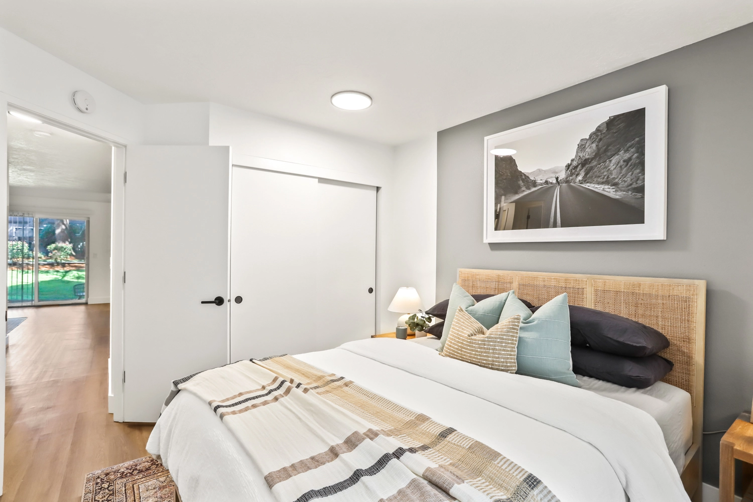 Bedroom with modern furniture, wood-style flooring, and closet with sliding doors.