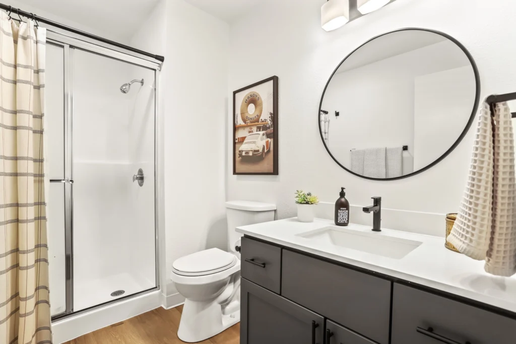 Bathroom with wood-style flooring, vanity with drawers and sink, and step-in shower.
