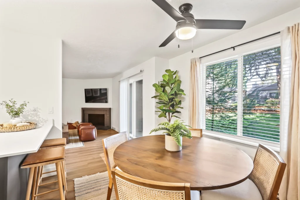 Dining area near kitchen and living room with natural light and ceiling fan.
