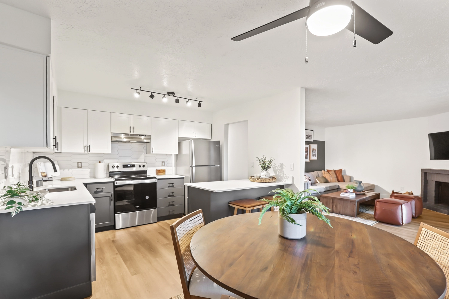 Dining area near kitchen and living room with natural light and ceiling fan.