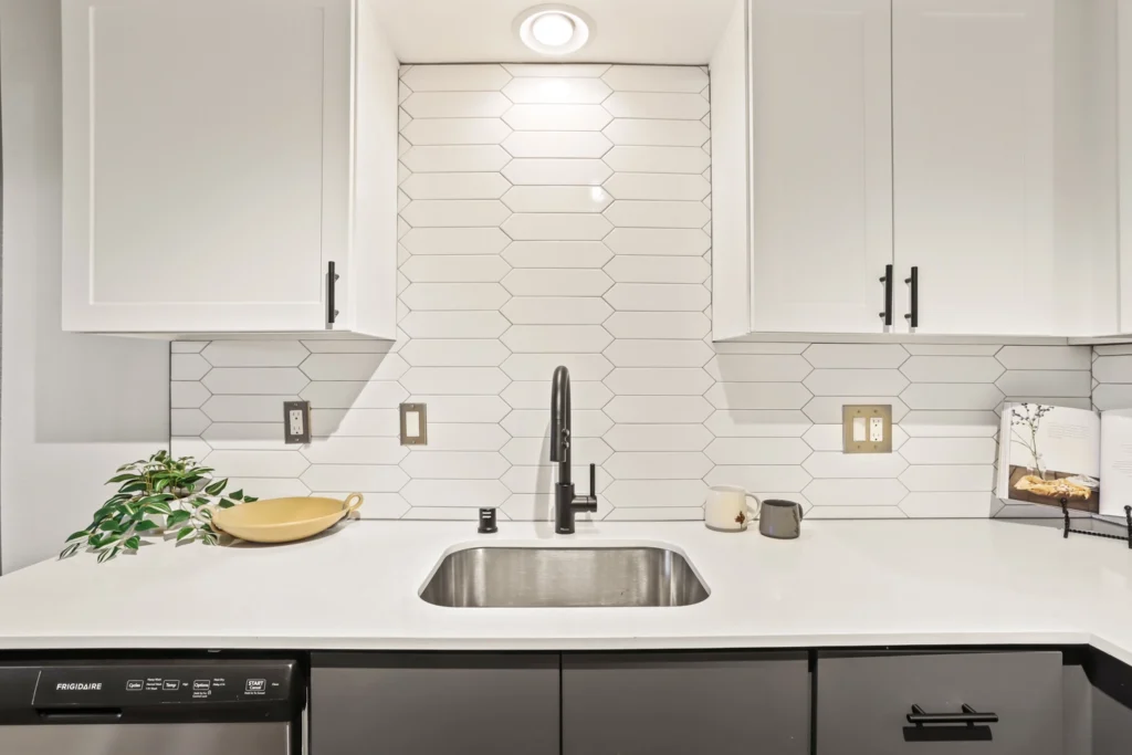 Kitchen with modern cabinetry, stainless steel appliances, and designer fixtures. Geometric tile backsplash.